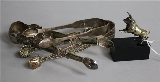 A pair of silver sugar tongs, two white metal pairs and a Spanish white metal bull.